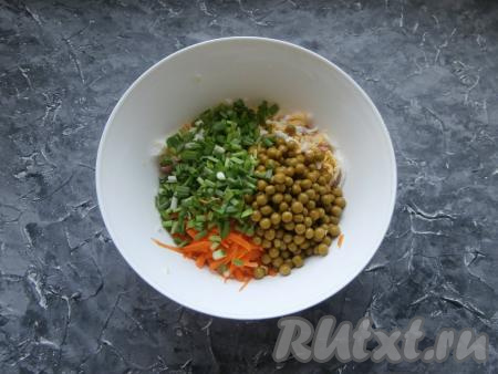 Сюда же выложить консервированный горошек без жидкости и измельчённый зелёный лук.