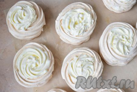 С помощью кондитерского мешка наполните остывшие белковые корзиночки кремом из взбитых сливок.