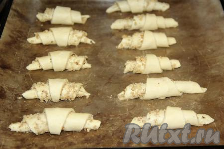 Выложить заготовки творожных рогаликов с ореховой начинкой на противень, застеленный пергаментом (или тефлоновым ковриком), и поставить в разогретую духовку.