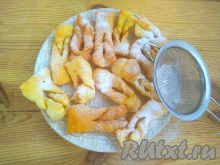 Переложить хворост на тарелку для подачи и присыпать сахарной пудрой через сито.