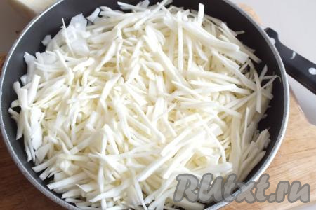 Пока дрожжи активируются, приготовим начинку, для этого капусту нарежьте тонкой соломкой. Очищенную луковицу нарежьте произвольно. В сковороду налейте 3 столовые ложки растительного масла, разогрейте, выложите нарезанные лук и капусту.