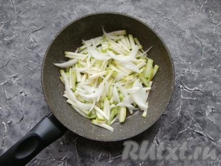 В сковороду влить растительное масло, разогреть,&nbsp;выложить кабачок, а также очищенный и нарезанный тонкими перьями репчатый лук.