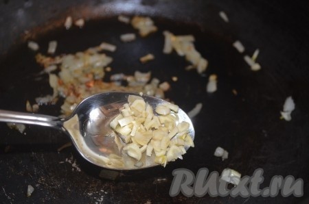 Добавить к луку порезанный чеснок и острый перец. Жарить еще 1 минуту.