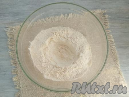 Муку с разрыхлителем просеять в миску, удобную для замешивания теста. В центре муки сделать углубление.