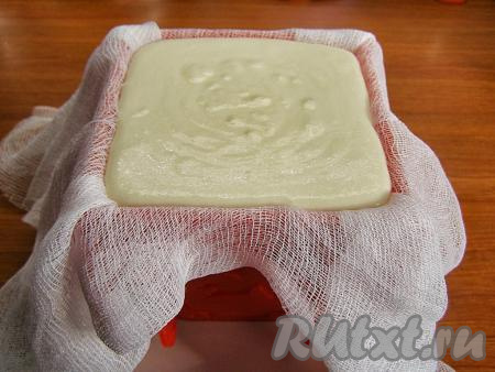 Формочку для пасхи ставим на тарелку вверх дном, выстилаем двумя слоями марли. Концы марли должны свисать с краёв формы. Выкладываем творожную массу в формочку для пасхи. Закрываем верх свисающими краями марли и убираем в холодильник, примерно, на час. На тарелку, на которой стоит формочка, будет стекать сыворотка, которую нужно аккуратно слить.