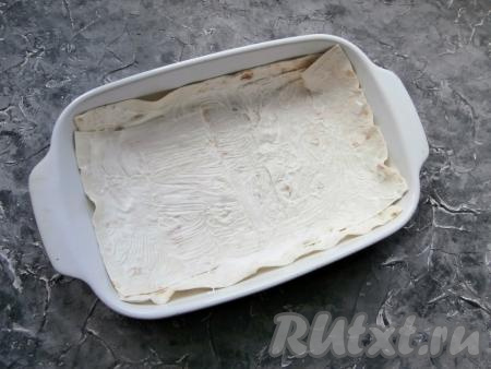 Лаваш нарезать на части так, чтобы он был по размеру формы, но края немного заворачивались на бортики формы. Выложить один лист лаваша, смазать немного оставшейся сметаной. На него - второй лист, также смазать сметаной.