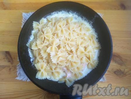 Добавить пасту в сковороду к сёмге в сливочном соусе, немного посолить и поперчить.