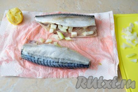 Рыбу посолите и посыпьте специями по вкусу внутри и снаружи. Сбрызните скумбрию лимонным соком. Это необходимо для того, чтобы удалить рыбный запах. Лук очистите, промойте и мелко нарежьте. Наполните рыбу внутри нарезанным луком.