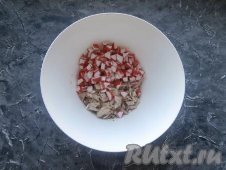Предварительно нужно отварить морковку и картошку в кожуре, курицу и яйца. Куриное мясо без кости варится в кипящей подсоленной воде 30-35 минут, картофель - 25-30 минут, морковь - минут 20, яйца - 8-10 минут. Всё остудить и очистить. Крабовые палочки достать заранее, чтобы они полежали при комнатной температуре и успели разморозиться. Нарезать мелко размороженные крабовые палочки, выложить в достаточно объёмный салатник, добавить нарезанное на небольшие кусочки куриное мясо.