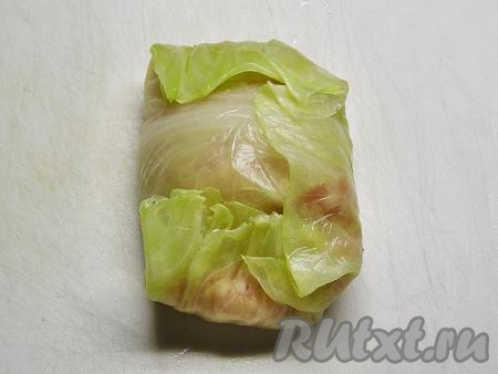 Накрываем фарш ближайшим концом листа, затем заворачиваем боковые края листа капусты и сворачиваем рулетиком, начиная с края с фаршем.