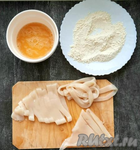 Промакнуть кальмаров бумажными салфетками, чтобы убрать лишнюю влагу. Муку насыпать в тарелку, добавить 1/2 чайной ложки соли, хорошо перемешать. Яйцо разбить в другую ёмкость и немного взбить вилкой, добавив 1/2 чайной ложки соли, яичный кляр готов.