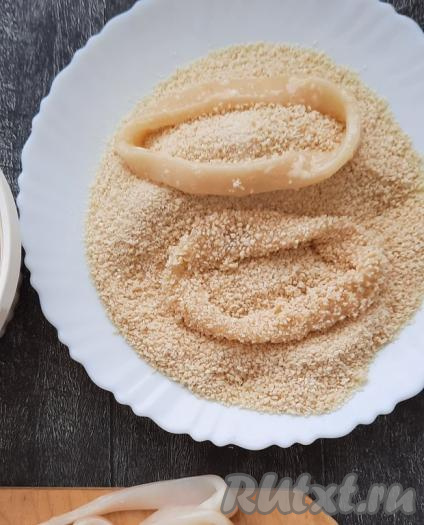 Далее каждое кольцо кальмара обвалять в панировочных сухарях со всех сторон так, чтобы колечки были полностью покрыты сухарями.