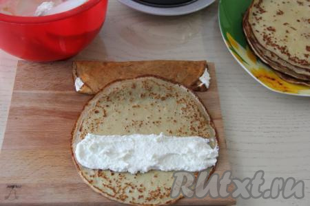 Творожная начинка получится однородной, в меру густой. На каждый блинчик выложить, примерно, 1,5 столовые ложки начинки в виде полоски шириной около 5 см (как на фото). Завернуть начинку в блин так, чтобы завёрнутый блин напоминал длинный прямоугольник шириной,&nbsp;примерно, 6 см.