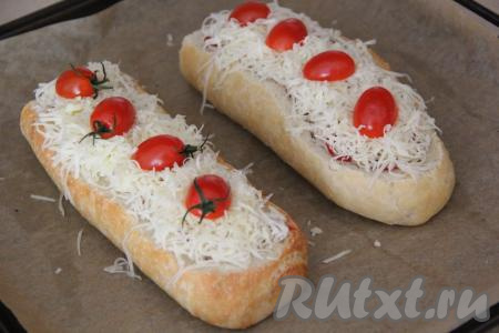 Половинки фаршированного&nbsp;багета переложить на противень, застеленный пергаментом. Выложить натёртый сыр поверх фарша пышной шапкой. Сверху разместить половинки помидоров черри.