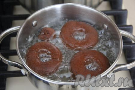 В кастрюле на среднем огне очень хорошо разогреть растительное масло (масла должно быть много, чтобы пончики могли быть покрыты до половины объёма). Аккуратно выложить пончики в закипевшее масло и жарить на среднем огне в течение 5 минут, периодически переворачивая.