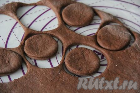 Хорошо поднявшееся тесто обмять и на присыпанной мукой поверхности раскатать скалкой в пласт толщиной, примерно, 1,5 см. Вырезать пончики любого размера. Можно для вырезания использовать перевёрнутую чашку, а дырки в пончиках вырезать пробкой от пластиковой бутылки.