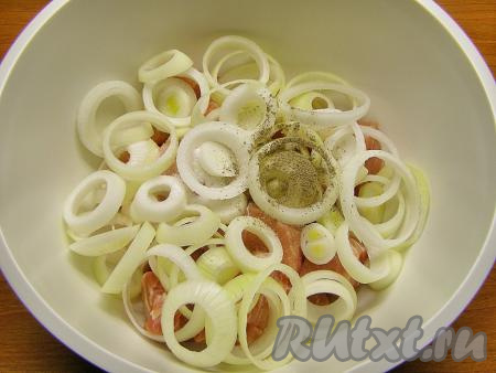 Перекладываем мясо в глубокую миску, сверху кладём кольца лука, добавляем соль и чёрный молотый перец, по желанию, можно добавить немного приправы для шашлыка.