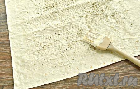 Расстелить на столе лист лаваша. Смазать его майонезом, оставляя свободными края (по 2 см с каждого края). Смазанную часть лаваша посыпать сушёными прованскими травами. Можно также использовать измельчённую свежую зелень (укроп, петрушку).