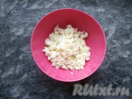 Нарезать остывшую цветную капусту на маленькие кусочки в миску.