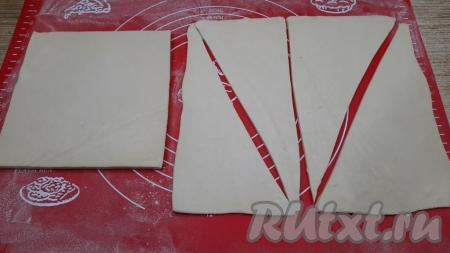 На поверхности, припылённой мукой, вначале один пласт размороженного теста раскатать с помощью скалки в одном направлении. Толщина раскатанного пласта должна быть, примерно, 3&nbsp;мм. Раскатанный пласт разрезать на 2 прямоугольника. Затем каждый прямоугольник разрезать по диагонали на 2 треугольника. Из одного&nbsp;пласта получатся 4 треугольника (как на фото). Аналогично подготовить 4 треугольника из второго пласта теста.