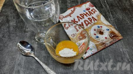 Пока круассаны с шоколадом из слоёного бездрожжевого теста выпекаются, возьмём яйцо и отделим желток от белка (белок нам в этом рецепте не понадобится). В отдельной ёмкости нужно соединить яичный желток, 1 столовую ложку холодной воды и 1 чайную ложку сахарной пудры, тщательно перемешать яично-сахарную смесь.