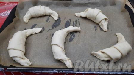 Выложить заготовки круассанов на застеленный пергаментом противень на расстоянии друг от друга. Выпекать в разогретой до 180 градусов духовке 20 минут.