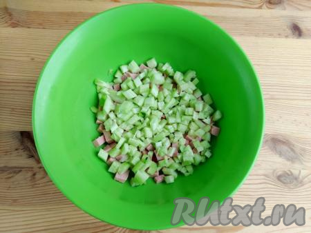 Огурец промыть, очистить от кожуры, нарезать на кубики того же размера, как нарезали и колбасу, выложить в миску.