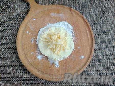 Скатать тесто на дощечке в шар, а затем сформировать лепёшку диаметром 3-4 см. По центру лепёшки выложить часть натёртого сыра.