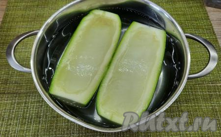 Взять достаточно объёмную кастрюлю, в неё должны полностью помещаться лодочки (как на фото). В кастрюле вскипятить воду, добавив в неё 1/2 чайной ложки соли. В кипящую воду опустить кабачковые лодочки на 2 минуты, затем сразу вынуть кабачки из кипятка и дать полностью остыть.