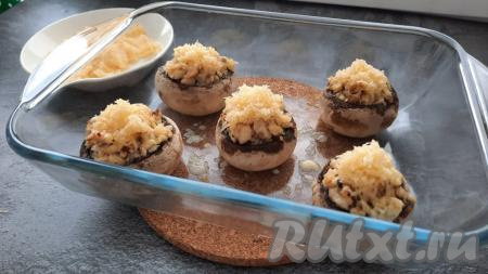 Через 20 минут достать фаршированные шампиньоны из духовки. На каждую шляпку выложить сыр, натёртый на мелкой (или средней) тёрке. Вернуть форму с грибами обратно в духовку ещё на 10 минут для того, чтобы сыр расплавился.