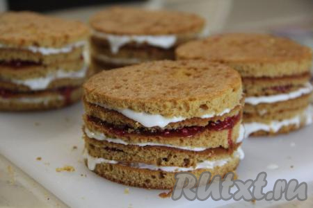 Сформировать медовые пирожные, выкладывая друг на друга 5 коржей, промазывая каждый корж сметанным кремом или ягодной начинкой. Я чередовала коржи: корж, промазанный сметанным кремом, чередовался с коржом, промазанным малиной с сахаром.