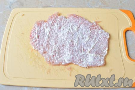 Для приготовления рулетов отлично подходит куриное филе. Разрежьте филе на тонкие части. Каждую часть куриного мяса немного отбейте кухонным молоточком. Чтобы мясо не рвалось при отбивании, накройте его пищевой плёнкой. Каждый кусочек отбитого филе немного смажьте сметаной, по вкусу посыпьте солью и специями.