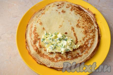 Выкладывайте на каждый блин по 1-5,2 столовые ложки начинки из яиц и зелёного лука, подверните края блинчика с боков к центру и сверните блин рулетиком.&nbsp;