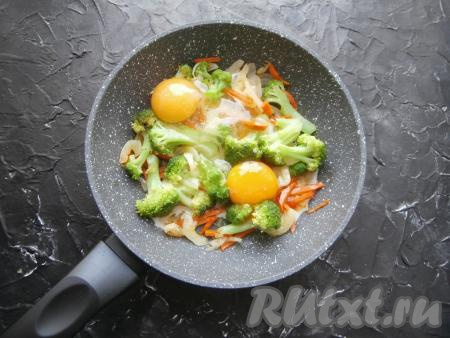 Посолить овощи по вкусу, перемешать и обжаривать в течение 3-4 минут, не забывая иногда перемешивать. Далее в сковороду с овощами разбить яйца, посолить их.
