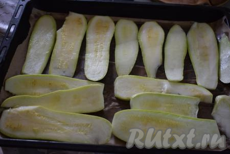 На противень выкладываем пергамент, смазанный 1 столовой ложкой растительного масла, и раскладываем пластины кабачка.
