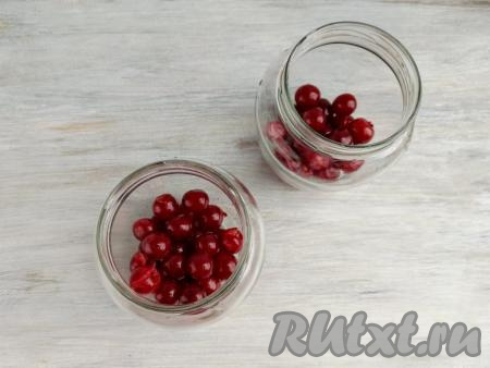 Банки промыть горячей водой с содой, сполоснуть тёплой водой. Простерилизовать банки удобным для вас способом. Я наливаю в банки по 100 мл воды и прогреваю в микроволновой печи 4 минуты на максимальной мощности, воду сливаю. Крышки прокипятить в течение 3 минут. Вишню перебрать, промыть в проточной воде, удалить хвостики. Равномерно распределить вишню по двум банкам.