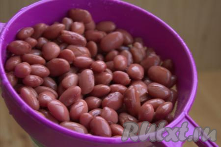 Консервированную фасоль достать из банки, выложить на сито. Промыть фасоль водой, а затем дать полежать в сите, чтобы стекла лишняя жидкость.
