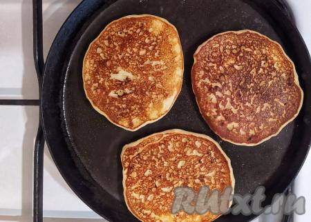 Выпекать банановые оладьи на медленном огне под закрытой крышкой по 2 минуты с каждой стороны (до золотистого цвета), затем переложить на тарелку. Аналогично пожарить все оладушки.