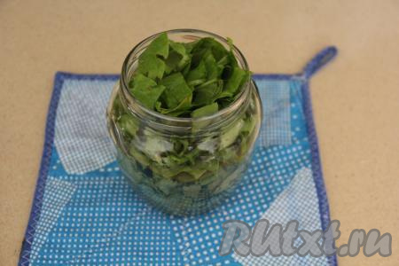 Выложить щавель в банку и слегка утрамбовать его, заполняя баночку до самого верха.