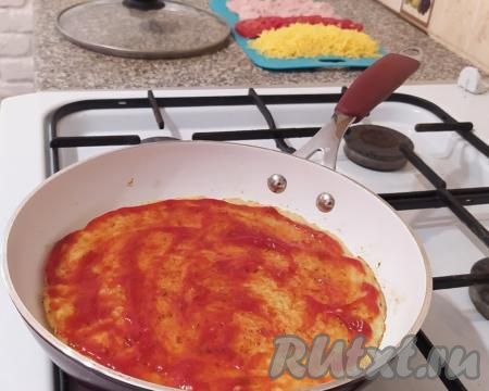 ​​​​​Перевернуть ещё раз, убавить огонь до самого минимума, смазать картофельную основу пиццы кетчупом (или томатным соусом).
