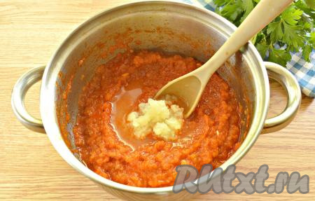 Пропускаем зубчики чеснока через пресс, выкладываем в небольшую ёмкость. Получившееся чесночное пюре заливаем уксусом и перемешиваем. Чесночно-уксусную кашицу выкладываем в аджику, тщательно перемешиваем и варим ещё минут 10.