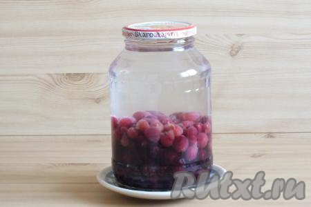 В горячую простерилизованную банку выложите подготовленные крыжовник и вишню. Залейте в банку крутой кипяток так, чтобы вода перелилась через край банки. Прикройте крышкой и оставьте на 20 минут на столе.