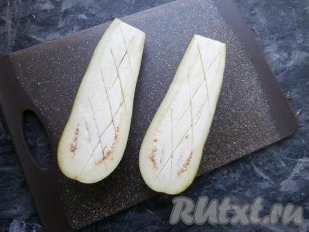 Вымытый баклажан разрезать пополам, а затем сделать на мякоти надрезы (как на фото) и либо отварить в кипящей воде в течение&nbsp;20 минут, либо запечь в разогретой духовке при температуре 180 градусов в течение минут 20, либо запечь в течение 5 минут в микроволновке при мощности 750 Ватт. Баклажан должен стать мягким, он будет достаточно легко отделяться от шкурки.