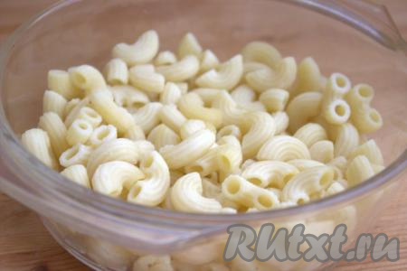Отварить макароны, для этого нужно вскипятить в кастрюле достаточно большое количество воды, подсолить, выложить макароны и отварить до готовности в течение времени, указанного на упаковке к вашим макаронным изделиям (макароны не должны перевариться, они должны стать мягкими, но при этом хорошо держать форму). Отваренные макароны (нам понадобится, примерно, 300 грамм варёных макарон) переложить в дуршлаг, чтобы стекла лишняя жидкость. Половину отваренных макарон ровным слоем выложить в&nbsp;подходящую форму для запекания.