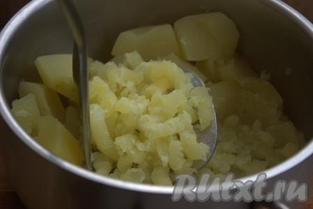 Затем слить из кастрюли всю воду и размять картофель с помощью толкушки в пюре.