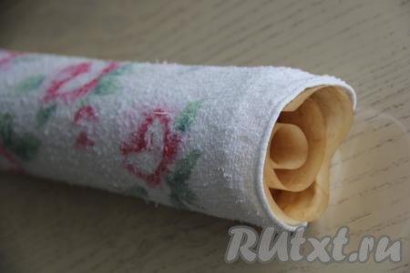 Свернуть корж вместе с пергаментом, на который вы его перевернули, в рулет.  Завернуть (или прикрыть) получившийся рулет полотенцем и оставить минут на 30.