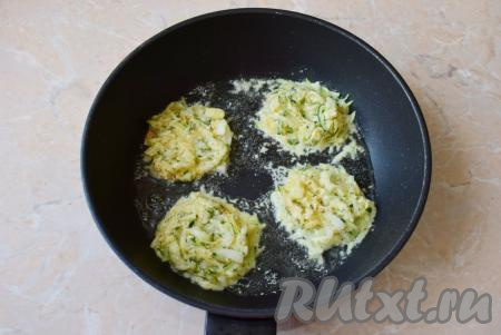 Для жарки разогрейте сковороду до горячего состояния на среднем огне и налейте немного растительного масла. Столовой ложкой выкладывайте по 1-1,5 столовых ложки кабачкового теста в виде оладий и обжаривайте вначале с одной стороны до румяности, затем переверните и готовьте до румяной корочки с другой стороны.
