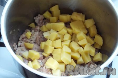 К обжаренному фаршу добавьте очищенный и нарезанный на кубики картофель. Обжаривайте, помешивая, в течение 5 минут.