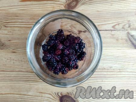 Ежевику перебрать, удаляя мятые и порченые ягоды. 100 грамм ежевики выложить в дуршлаг. Промыть ягоды под краном с рассекателем, не допуская сильного напора воды, чтобы не повредить нежные плоды. Банку, в которой будет закрываться компот на зиму, предварительно простерилизовать удобным вам способом, крышку поместить в воду и после начала кипения воды стерилизовать минуты 2-3. В банку выложить подготовленную ежевику.