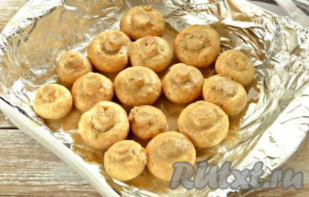 Форму для запекания застилаем фольгой. Выкладываем замаринованные шампиньоны шляпками вниз. Поливаем их оставшимся маринадом.